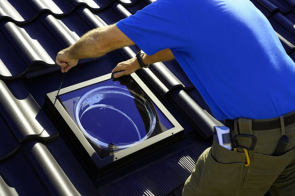 roofer repairing sun tunnel on pitched tile roof